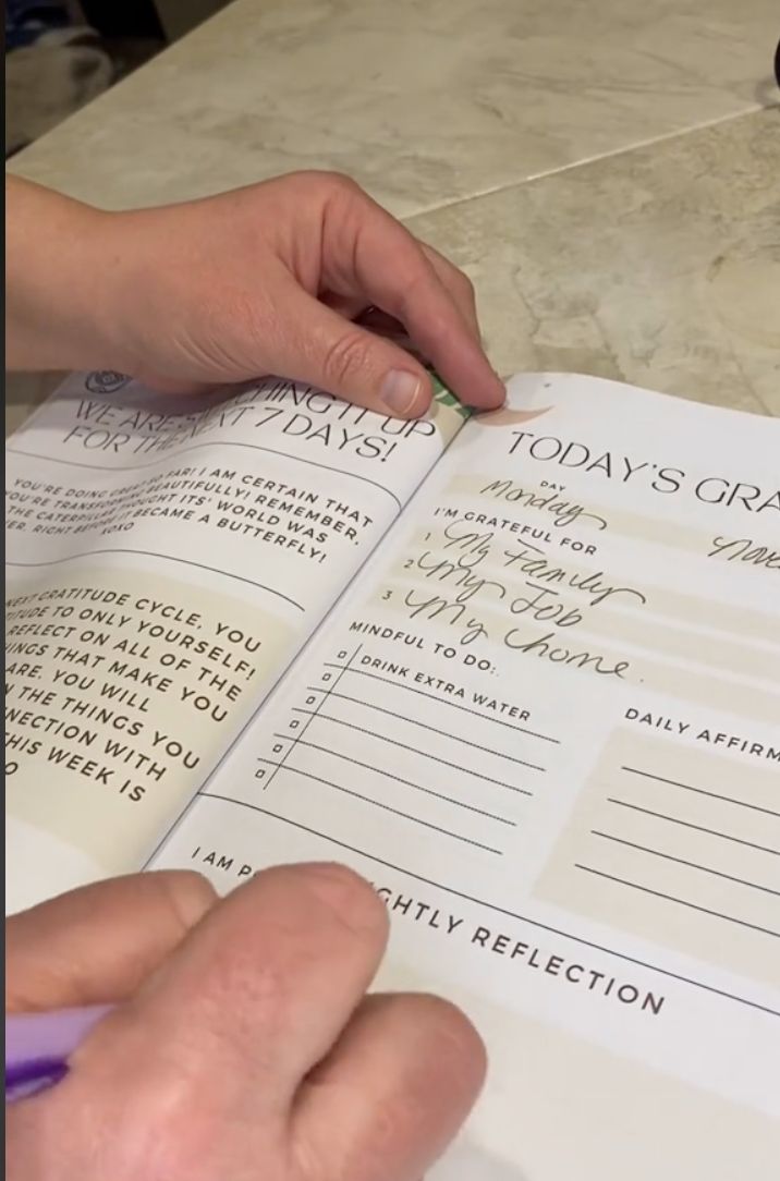 A reader's hand writing My Family, My Job and My home on a Today's Gratitude page.